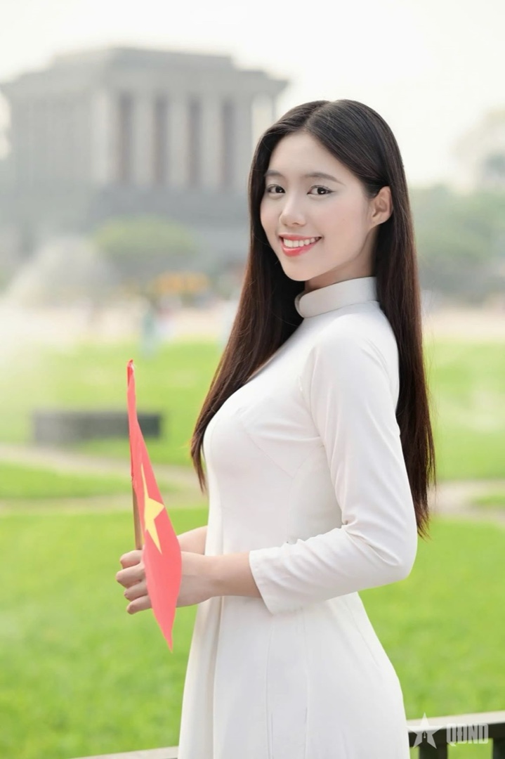 Thiếu nữ Việt Nam rạng rỡ trong tà áo dài trắng cầm cờ đỏ sao vàng